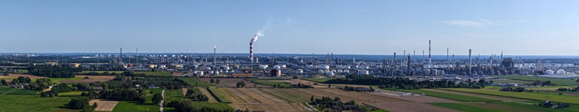 Aerial view of the PKN Orlen refinery featuring industrial towers, storage tanks, and smoke stacks surrounded by vast agricultural fields in Plock, Masovian Voivodeship, Poland.
