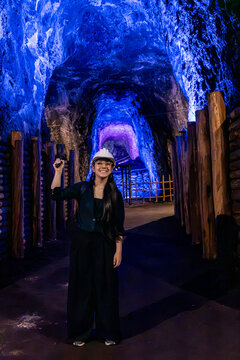Woman Tourist in Safety Hard Hat Standing in Blue Lit Mine Tunnel. Salt Mine - Nemocon