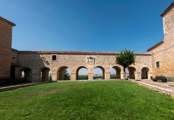 Fototapeta premium Mirador de los Arcos in Lerma, Burgos, Castile y Leon, Spain, featuring historic stone arches, a crest, and a green courtyard with views over the Castilian countryside under a clear blue sky.