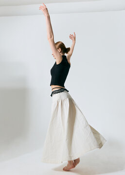 A sophisticated girl is spinning in a long light skirt