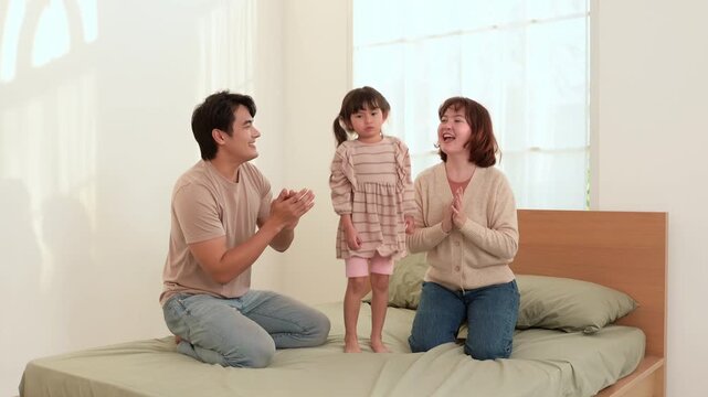 Family Plays Together on Bed With Girl Laughing and Parents