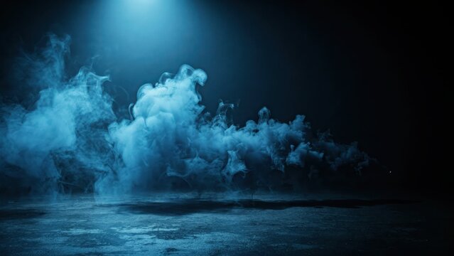 Thick blue smoke clouds on a dark stage floor under a spotlight for dramatic scene effects.