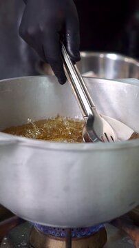 Chef putting fresh raw fish steak into hot boiling oil in a cauldron, close-up