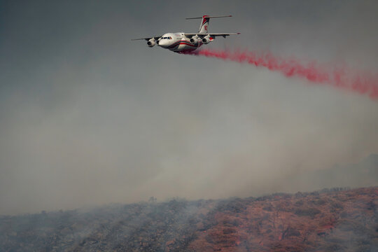 BAe 146 firefighting airtanker operated by Aero-Flite, Inc. releasing massive red retardant plume over smoke-filled hill