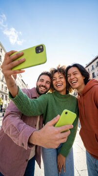 Buoyant friends taking smartphone selfie against a clear blue city sky