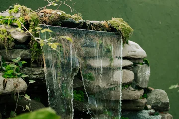 Fotobehang Badkamer Mossy waterfall cascading over stones in a quiet garden  © Darius