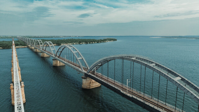 Aerial view of the Godavari Arch Bridge spanning the Godavari River with its distinctive steel arches and railway tracks, surrounded by calm water in Rajamahendravaram, Andhra Pradesh, India.