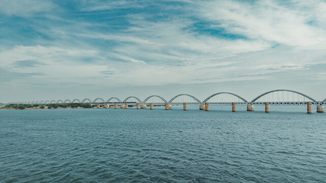 Aerial view of the Godavari Arch Bridge spanning the wide Godavari River under a clear blue sky in Rajamahendravaram, Andhra Pradesh, India.