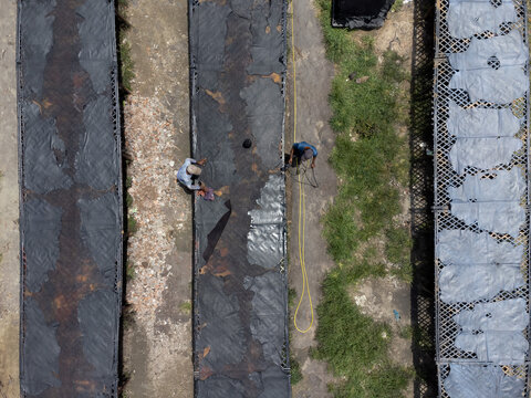 Aerial view of workers processing and drying animal hides on racks in an open area in Dhaka, Bangladesh.