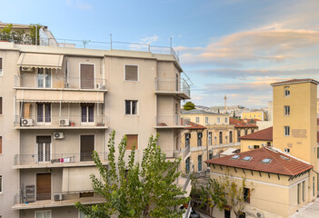 Fototapeta premium Residential apartment buildings and tiled rooftops beneath evening clouds in Kolonaki Athens