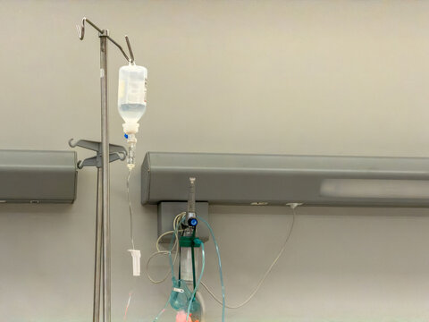IV fluid bag and oxygen mask at empty clinical treatment station with copy space