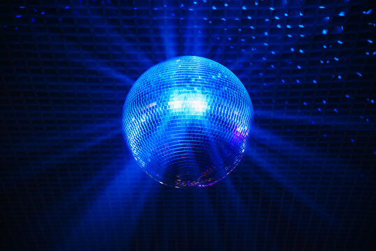 disco ball with mirror surface and bright rays, blue light, hanging on ceiling, night party background