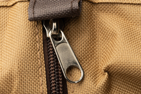 Close up of a zipper on a brown fabric bag