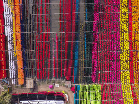 Aerial view of colorful fabrics hanging in long rows to dry under the sun in a textile dyeing area in Narayanganj, Dhaka, Bangladesh.