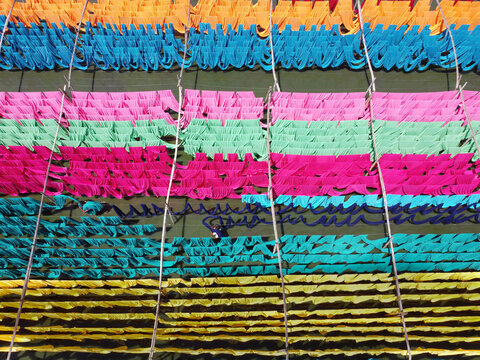 Aerial view of vibrant colorful fabrics hanging in long rows to dry in the sun at a textile facility in Narayanganj, Dhaka, Bangladesh.