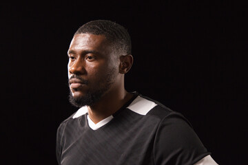 Obraz premium African man posing under studio lighting wearing black athletic shirt with white trim