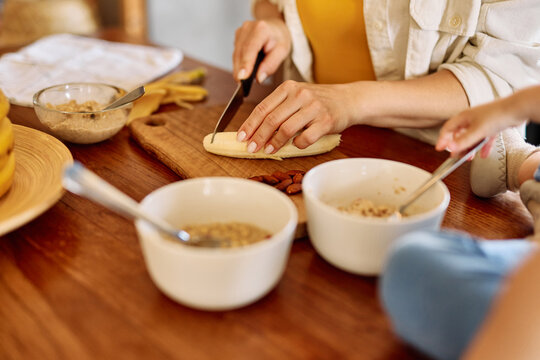 Portrait of a mother and daughter preparing and eating breakfast and having fun in the kitchen at home
