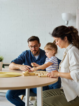 Portrait of a happy amily at home, having fun playing wooden brick challenge game, playing board game jenga at home