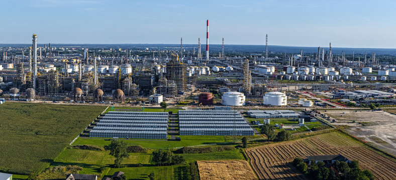 Aerial view of the extensive PKN Orlen refinery complex featuring industrial towers, storage tanks, and processing units surrounded by agricultural fields in Plock, Masovian Voivodeship, Poland.