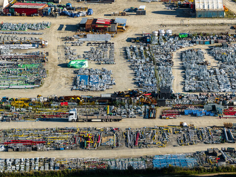 Aerial view of the industrial storage yard at the PKN Orlen refinery, featuring rows of metal pipes, equipment, and a truck driving through the site in Plock, Masovian Voivodeship, Poland.