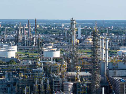 Aerial view of the PKN Orlen oil refinery complex featuring tall distillation columns, storage tanks, and industrial piping under a clear sky. Plock, Masovian Voivodeship, Poland.