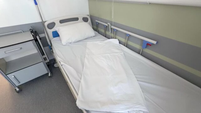 An empty hospital bed is made with white linen