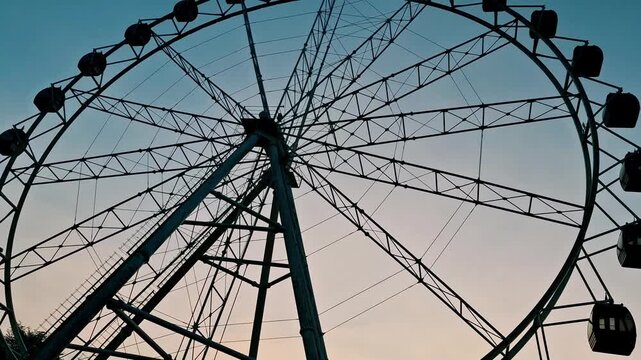 Ferris wheel construction in the morning with a clear blue sky, featuring a sturdy amusement ride in a children&rsquo;s playground located in the heart of the city. Urban entertainment, recreation, tourism.