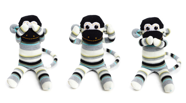 Three toy monkeys isolated on white background with hands on eyes, ears and mouth