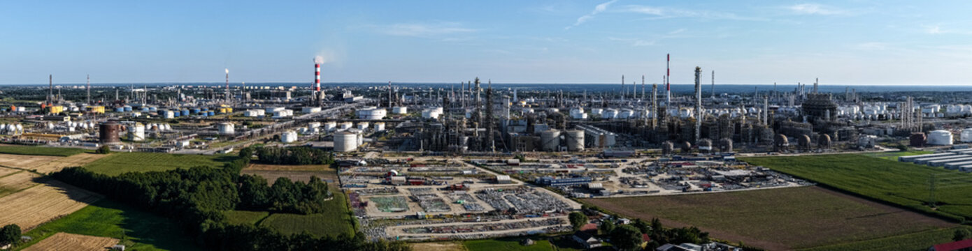 Aerial view of the PKN Orlen refinery complex featuring industrial infrastructure, storage tanks, and tall chimneys under a clear blue sky in Plock, Masovian Voivodeship, Poland.
