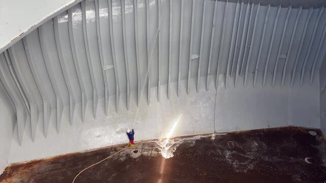 seafarer washing cargo hold of bulk carrier ship.