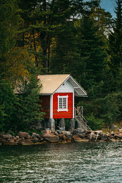 Small Red Wooden Cabin Hidden in Forest on the Shore