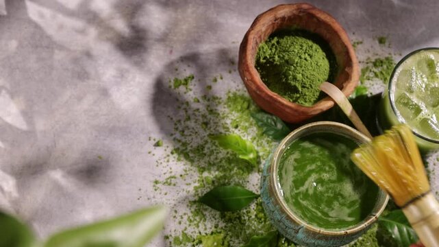 Hand whisking vibrant green matcha tea with traditional bamboo whisk, surrounded by matcha powder and tea-making ingredients. Illuminated by natural sunlight, creating an authentic tea ceremony scene