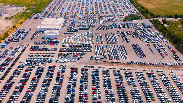 Large parking lot filled with cars during daytime in an open area. A large parking lot filled with many cars during the daytime. The area is open and spacious.