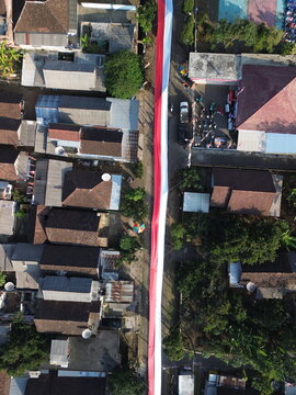 Aerial view of a long red and white Indonesian flag stretched along a residential street in Wonosari, East Java, Indonesia.