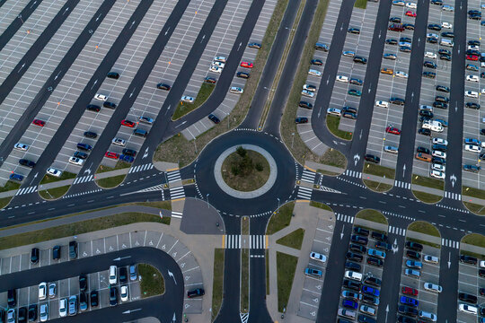 Aerial view of a large parking lot with a central roundabout and numerous parked cars arranged in orderly rows in Poland.