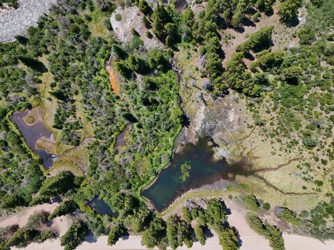 Aerial view of Sheep Gulch Trailhead featuring small ponds, dense pine forests, and a dirt road in the wilderness in Buena Vista, Colorado, United States.