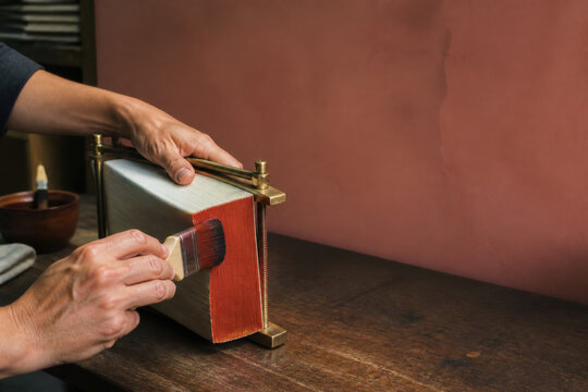 Hands Painting Vermilion Book Edges in Traditional Bindery with Copy Space