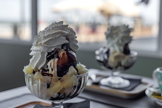 Ice cream sundae layered with pineapple pieces, vanilla scoop, chocolate sauce, and whipped cream