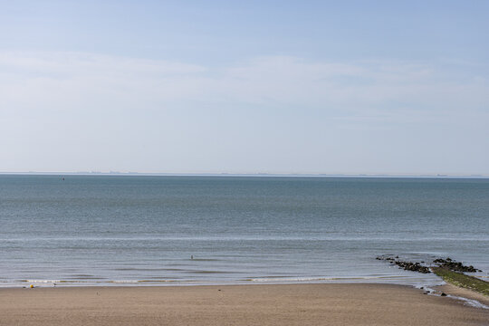 Calm wide sandy beach meeting the tranquil sea waters under a clear sky in Westende - Belgium