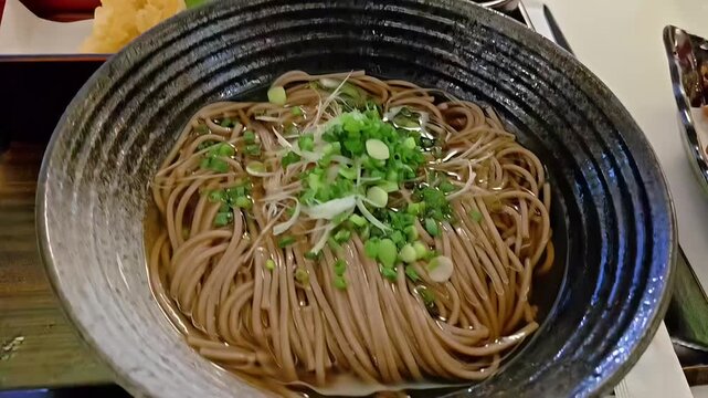 Steaming hot Soba buckwheat noodle with ebi tempura prawns, Japanese Food Cuisine, Healthy Meal, Scallion Garnish, Panning Slow Motion
