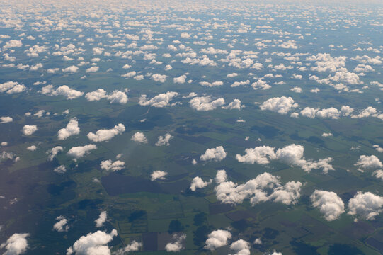 Vast cumulus clouds blanket rolling farmland beneath endless sky