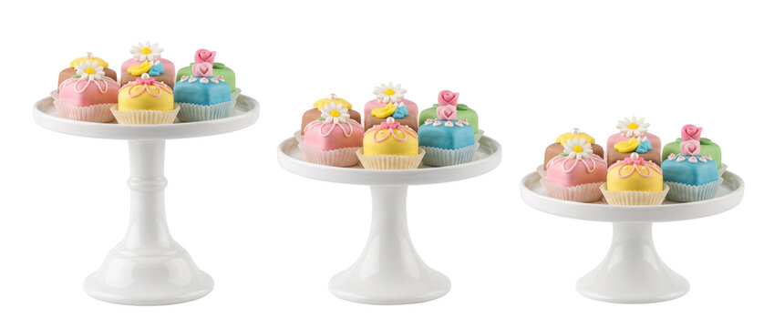 Mini cake petit four dessert decorated with fondant flowers on white pedestal stand for high tea party celebration, gourmet sweet bakery catering treats isolated on white background set