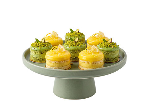 Lemon pistachio mini cakes display arranged on ceramic cake stand isolated on black background for gourmet bakery dessert catering menu presentation elegant sweet food treats pastry concept design