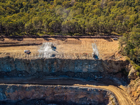 Aerial view of Boral Quarries showing excavation work with heavy machinery and surrounding forest in Whiteside, Queensland, Australia.