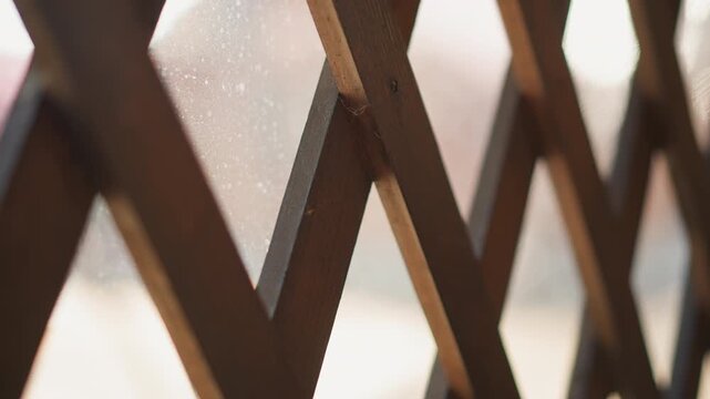 Tight low-angle view of rusted metal lattice with intersecting diagonal bars forming diamond shapes, flaking paint, textured corrosion, weathered brown tones and soft focus variation across surface
