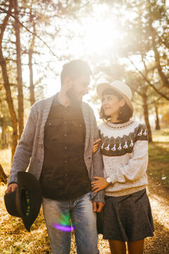A loving couple spends time together in a sunny forest. A young woman and man, dressed stylishly, stroll and relax on an autumn day at sunset. The concept of love, relaxation, and enjoyment.