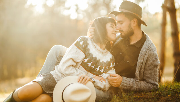 A loving couple spends time together in a sunny forest. A young woman and man, dressed stylishly, stroll and relax on an autumn day at sunset. The concept of love, relaxation, and enjoyment.