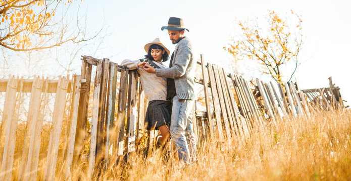 A loving couple spends time together in a sunny forest. A young woman and man, dressed stylishly, stroll and relax on an autumn day at sunset. The concept of love, relaxation, and enjoyment.