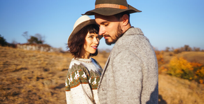 A loving couple spends time together in a sunny forest. A young woman and man, dressed stylishly, stroll and relax on an autumn day at sunset. The concept of love, relaxation, and enjoyment.