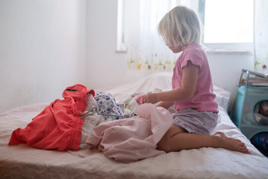 Little Girl Sorting Clean Laundry on the Bed